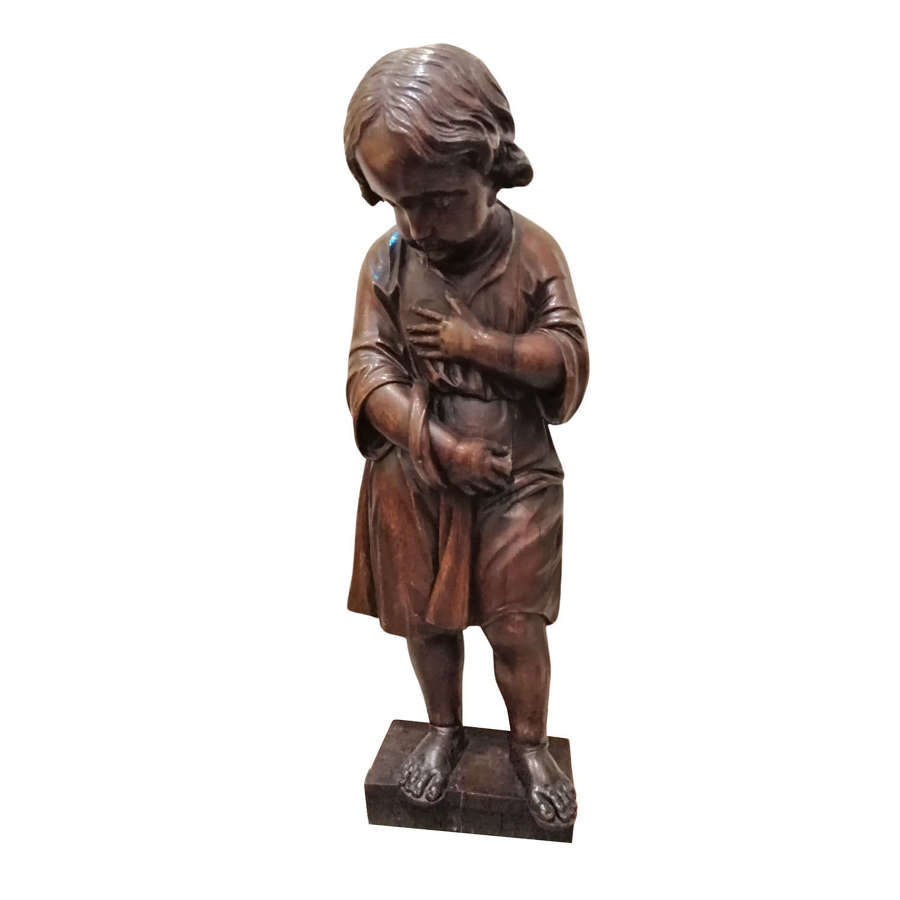 A 17th century Flemish carved wooden figure of a young boy