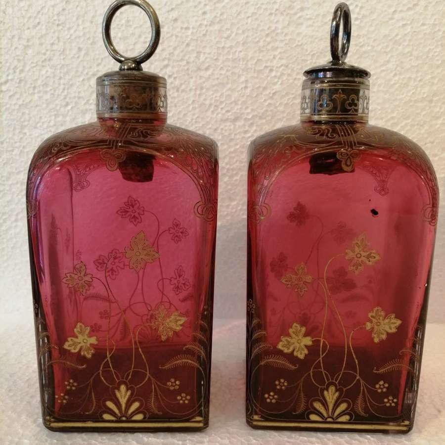 A pair of cranberry & gilt decorated square decanters