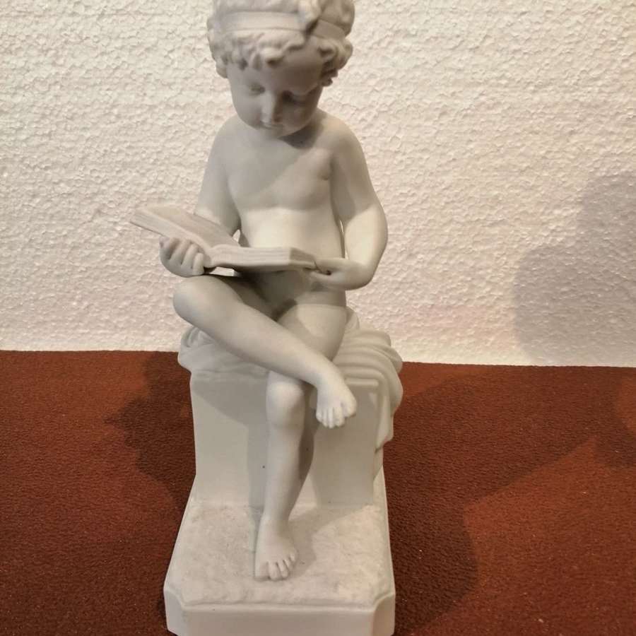 A Parianware or bisque figure of boy reading book